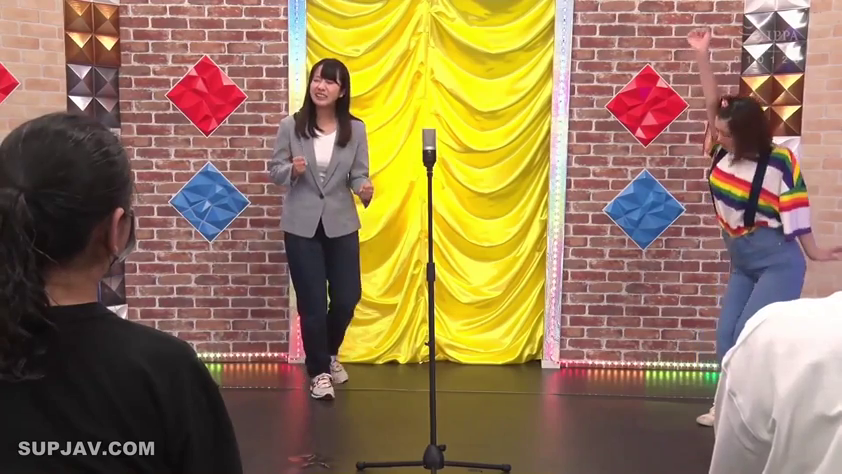 全身 · 彩虹条纹衫 · 兴奋 · 演播室舞台 · 站立舞动 · 节目表演 · 麦克风架 · 综艺现场