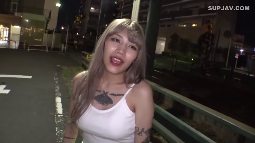 站立 · 中景 · 微笑 · 面对镜头 · 白色背心 · 纹身 · 室外街道